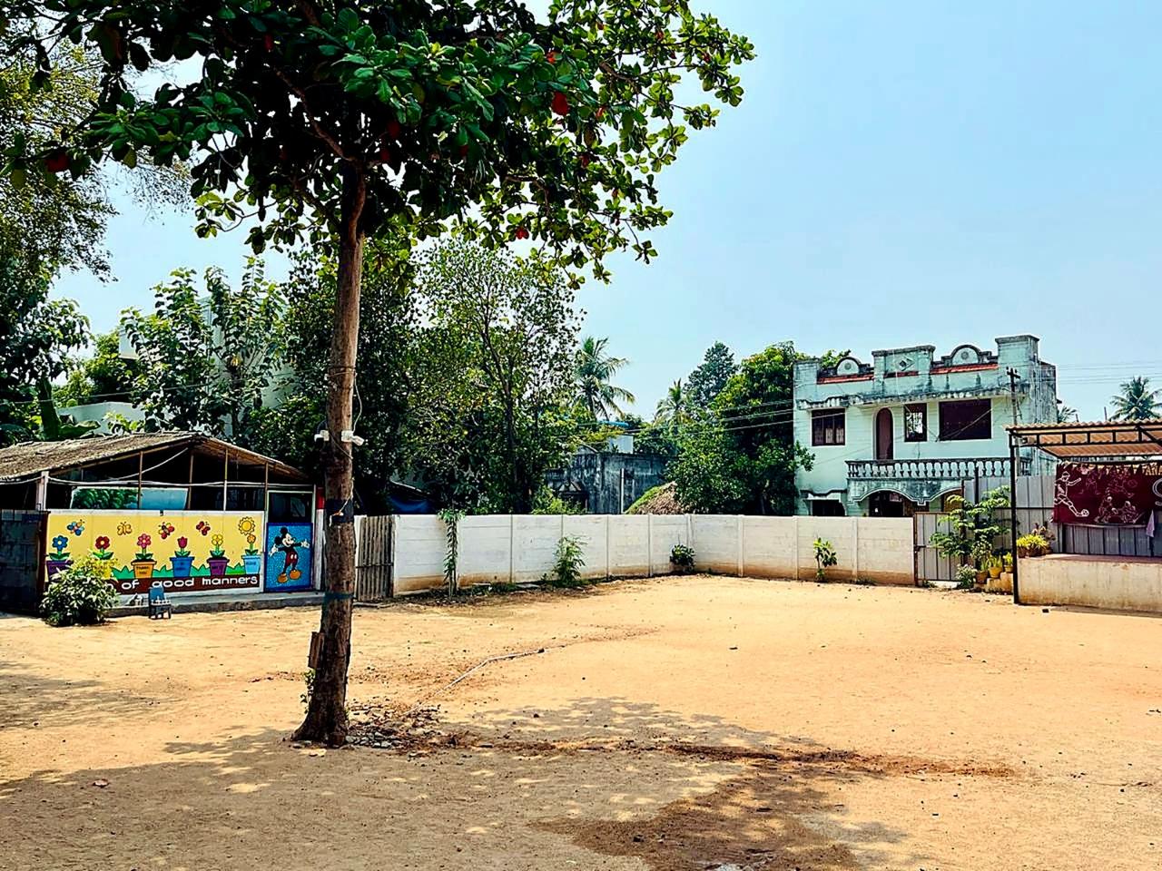 Open school play ground with shade trees and activity mural wall